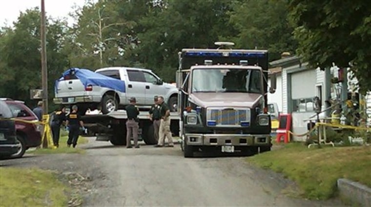 This cell phone photo shows law enforcement officials standing near a silver pickup truck being removed Wednesday from where it was parked near the home of Celina Cass, in Stewartstown, N.H.